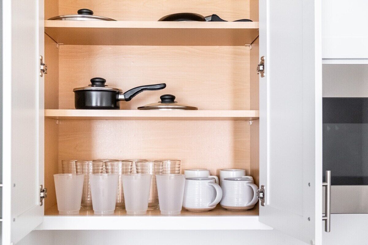 Un armario de cocina con repisas que contiene utensilios de cocina y cristalería.