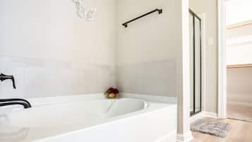 A modern bathroom with a white bathtub, a black towel rack, and a glass shower enclosure.