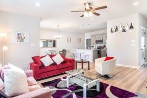 A modern living room with a red sofa, a white armchair, and a glass coffee table.