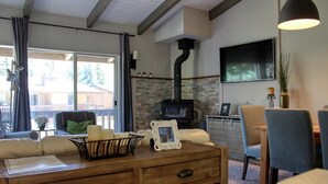 Un salon avec une cheminée, un téléviseur et un coin repas avec des chaises.