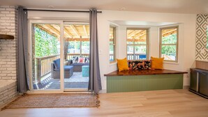 Een kamer met een schuifdeur naar een buitenterras, een ingebouwde bank met kussens en uitzicht op de omgeving.