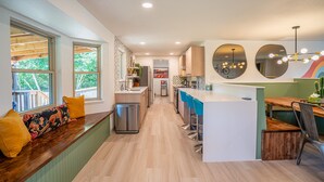 Een moderne keuken met een centraal eiland, barkrukken en een zithoek met kussens.
