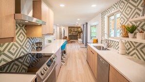 Een moderne keuken met een centraal eiland, roestvrijstalen apparatuur en een decoratieve spatwand.