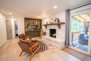 Uma sala de estar com lareira, área de jantar e vista para o exterior.