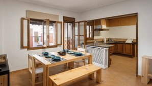 A compact kitchen with wooden cabinets, a dining table with benches, and a small island.