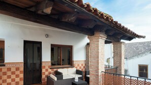 A covered patio with outdoor furniture, a tiled floor, and a brick pillar.