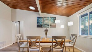 Un comedor con una mesa y sillas de madera, un cuadro en la pared y una ventana con vistas.