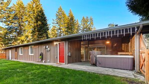 Una casa moderna con un porche cubierto, una puerta roja y un jacuzzi.