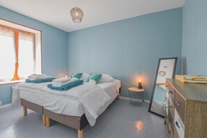 Un dormitorio con cama, mesita de noche, cómoda y ventana con cortinas.