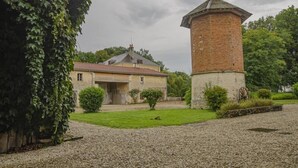 Un edificio con una torre de ladrillo y una casa de piedra con tejado de tejas.