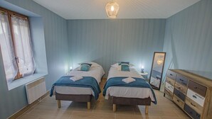 Un dormitorio con dos camas, un aparador, un espejo y una ventana con cortinas.