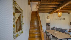 Una escalera de madera que conduce a un comedor con una mesa y sillas de madera.