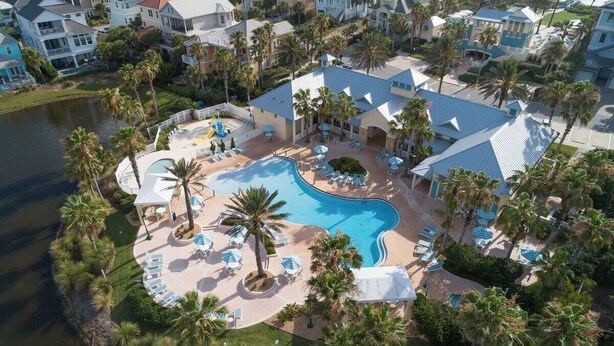 An aerial view of a resort with a large swimming pool surrounded by palm trees and lounge chairs. - The BEST View at Cinnamon Beach- Largest Ocean Unit, Sunrise and Sunset! (Palm Coast)