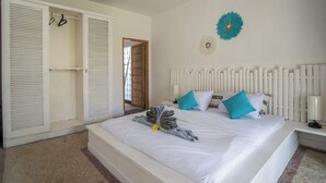 A bedroom with a bed, white headboard, and a ceiling fan.