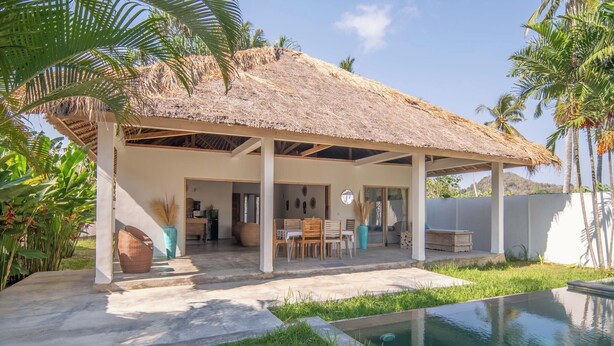 A covered outdoor area with a pool, a dining table, and chairs.