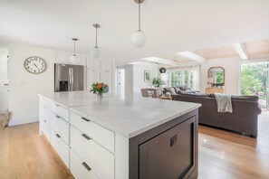 Una cocina moderna con armarios blancos, una isla grande e iluminación colgante.