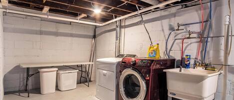 A laundry room with a washing machine, a sink, and a bench.