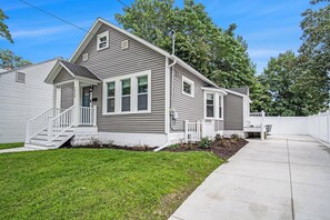A two-story house with a front porch, a small deck, and a covered patio area.