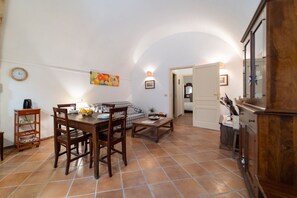 A dining area with a wooden table and chairs, a sofa, a coffee table, and a kitchen area with cabinets.