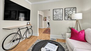 A modern living room with a mounted TV, a bicycle, a sofa, and a coffee table.