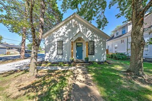 A small, single-story house with a front porch, a blue door, and two potted plants on either side. - .2 mi to Downtown Rogers, Heated pool on Bike Trail, King Bed, Fire table (Rogers)