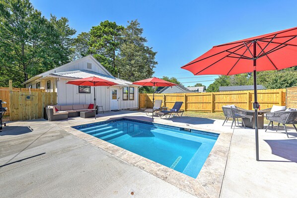 A backyard with a swimming pool, red umbrellas, and outdoor furniture. - .2 mi to Downtown Rogers, Heated pool on Bike Trail, King Bed, Fire table (Rogers)