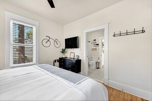 A bedroom with a bed, a dresser, a television, and a coat rack. - .2 mi to Downtown Rogers, Heated pool on Bike Trail, King Bed, Fire table (Rogers)