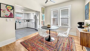 A modern kitchen with white cabinets, a black refrigerator, and a dining area with a round table and white chairs.