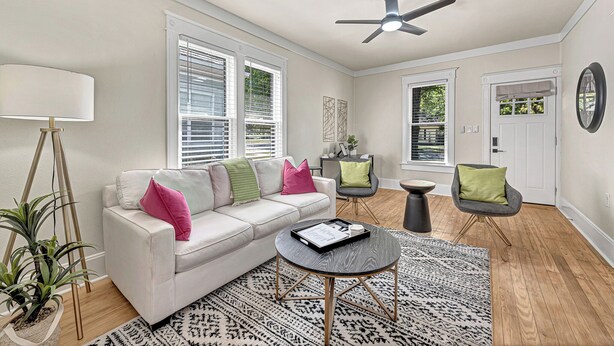 A modern living room with a white sofa, a round coffee table, and a ceiling fan.
