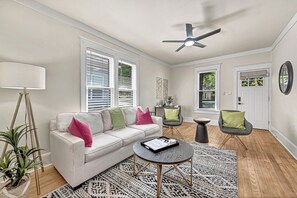 A modern living room with a white sofa, a round coffee table, and a ceiling fan. - .2 mi to Downtown Rogers, Heated pool on Bike Trail, King Bed, Fire table  (Rogers)
