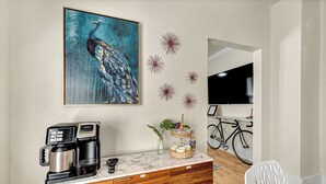 A kitchen with a coffee maker, a decorative wall piece, and a bicycle in the background.