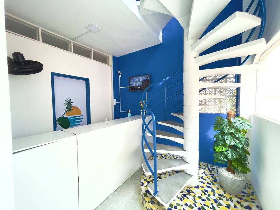 A modern interior with a blue accent wall, a white reception desk, a spiral staircase, and a potted plant.