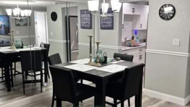 A dining area with a rectangular table and four chairs, a chandelier above, and a clock on the wall. - On the beautiful lake, it is close to the airport, malls,restaurants ,beach etc. (Lauderhill)