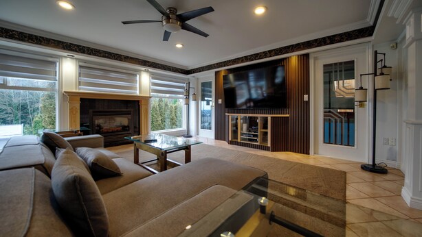 A spacious living room with a large TV, comfortable seating, a fireplace, and a view of the outdoors.