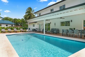 A swimming pool with lounge chairs and a covered patio area.
