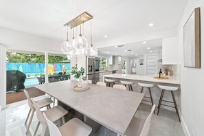 Una cocina moderna con una isla grande, electrodomésticos de acero inoxidable e iluminación colgante.