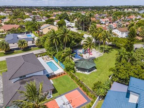 Vista aérea de una zona residencial con casas, un parque infantil y una cancha de tenis.