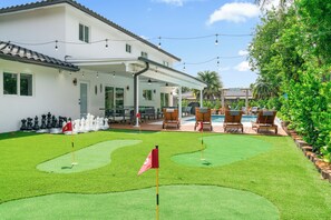 A house with a covered patio, a swimming pool, and a putting green.