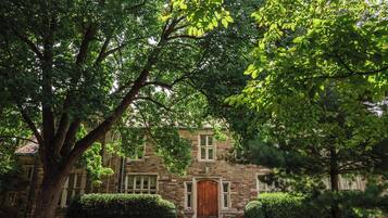 A stone building with a central entrance, surrounded by well-maintained lawns and trees.