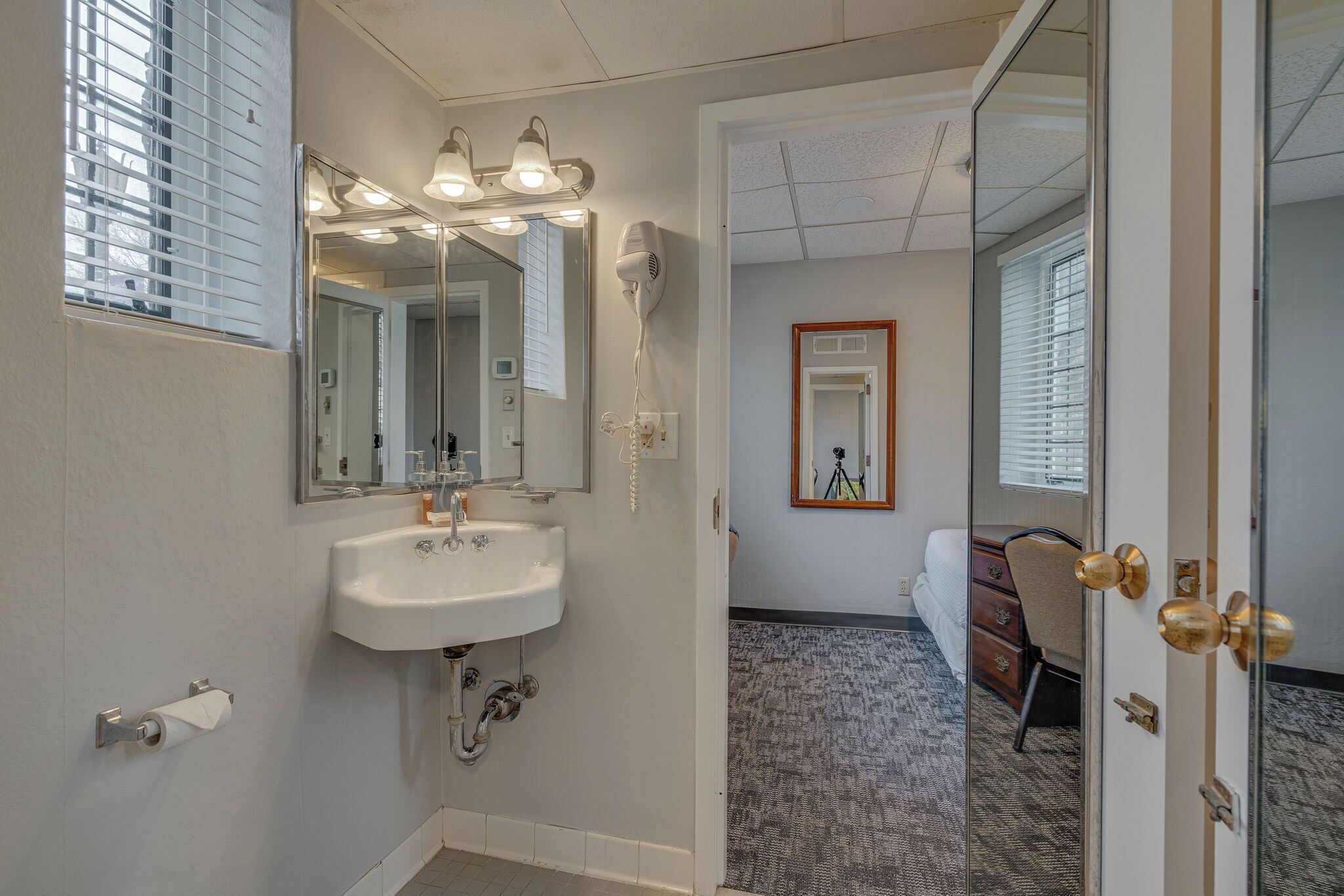 A bathroom with a sink, mirror, and a hairdryer.