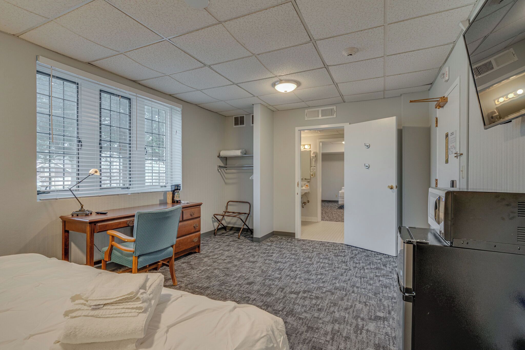 Een hotelkamer met een bed, bureau, stoel en een kitchenette.