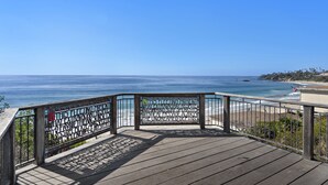 Eine Holzterrasse mit Metallgeländer, das auf das Meer blickt.