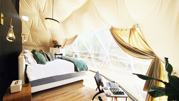 A cozy bedroom with a bed, bedside table, lamp, and a window with curtains.