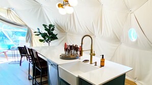 A modern kitchen with a central island, a sink, and a dining area with chairs.