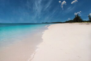 Een strand met helder turquoise water en wit zand.