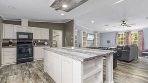 Una cocina moderna con armarios blancos, una isla central y un área de comedor con sofá gris.