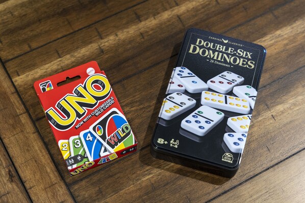 A UNO card pack and a set of Double-Six dominoes on a wooden surface.