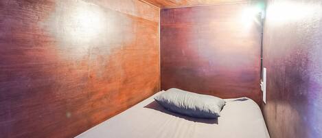 Una habitación pequeña y acogedora con paredes de madera y una cama individual con almohada.