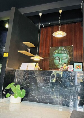 Una mesa de recepción con una estatua de Buda, estantes de madera y una encimera de mármol.