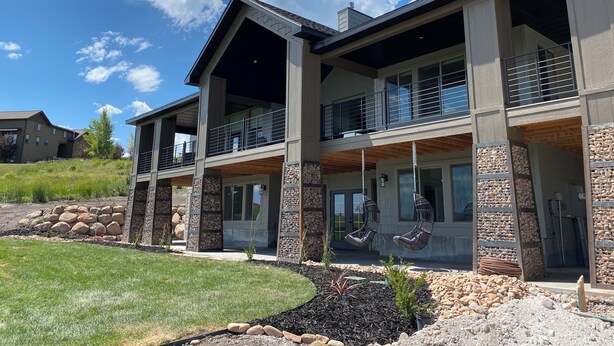 A modern two-story house with a stone facade, large windows, and a balcony.